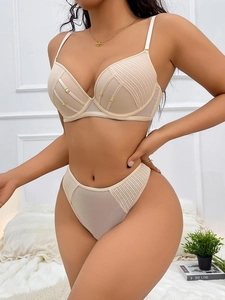 Dettaglio del set lingerie beige con trama a coste e pannelli in rete con anelli d'oro