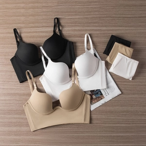 Flat lay of seamless deep U bra sets in black, white, and beige colors on a wood surface
