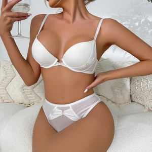 Detail of white mesh lingerie set with golden metal rings and delicate buckle accents
