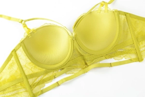 Detail of yellow lace bra showing push-up cup lining and intricate mesh fabric textures