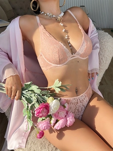 Detailed view of floral lace lingerie set in peach pink worn by a model in a cozy setting