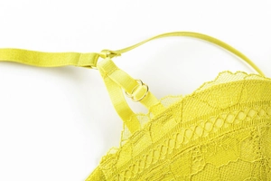 Detail of floral lace fabric and adjustable shoulder strap on fluorescent green bra