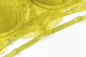 Close-up of acid green floral lace texture and dual straps with gold metal buckles