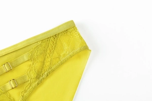 Detailed close-up of yellow floral lace fabric and golden metal adjustment buckles