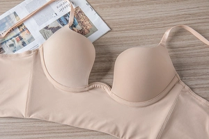 Detail of skin-colored seamless U-shaped push-up bra on a textured wooden background