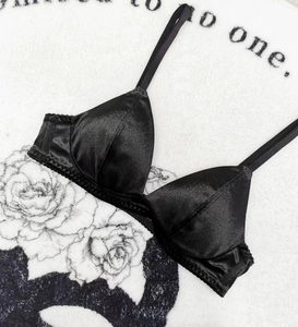 Détail d'un soutien-gorge triangle en satin noir avec fines bretelles et dentelle