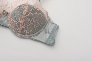 Detail of light blue satin bra with pink floral eyelash lace and breathable mesh wings