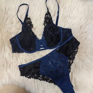 Flat lay of navy blue lace lingerie set with fine embroidery on white faux fur background