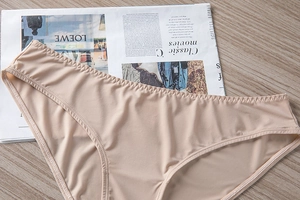 Detailed close-up of seamless beige panties with scalloped wavy edges on smooth fabric