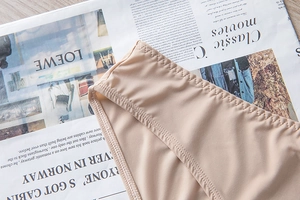 Detailed close-up showing the precise zigzag stitching on seamless nude-colored lingerie fabric