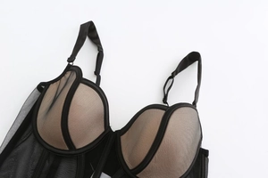 Dettaglio del corsetto con pizzo a rete nero, stecche di sostegno e spalline regolabili