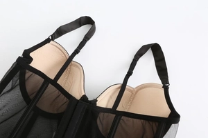 Dettaglio del corsetto in rete nera con coppe imbottite e spalline regolabili