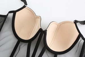 Dettaglio di un corsetto in rete nera trasparente con coppe imbottite e ferretto