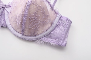 Macro shot of delicate floral eyelash lace detail and purple bow on underwire bra