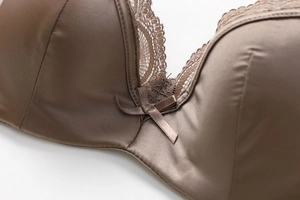 Close-up of brown satin bra with floral lace trim and delicate bow detail on front
