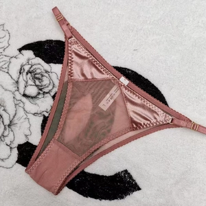 Dettaglio perizoma in raso rosa cipria e mesh trasparente con fibbie dorate