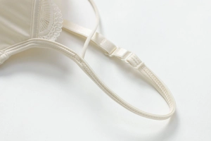 Detailed close-up of adjustable strap and lace edge on a cream satin bra