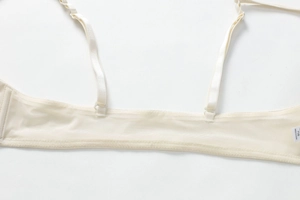 Detailed close-up of breathable mesh back band and elastic straps on a cream lace bra