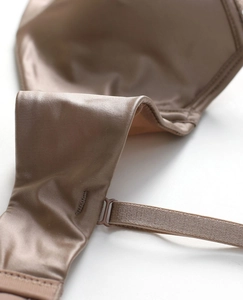 Detailed macro view of tan satin fabric texture and adjustable strap on the lace bra