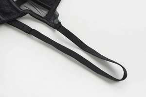 Detail of adjustable black elastic strap and floral lace on a delicate bra with gold buckle