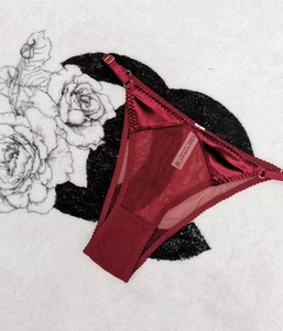 Detail of burgundy velvet and mesh thong with adjustable gold hardware and lace trim