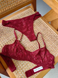 Détail d'un ensemble de lingerie en dentelle rouge foncé avec étiquette sur rotin