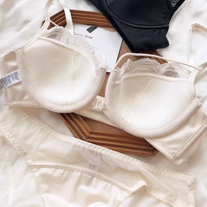 Detail of French beige lace lingerie set with front closure on white silk fabric background