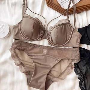 Detailed view of coffee brown lace lingerie set with silk-finish bra on white bedding