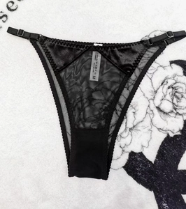 Detail of black lace and silk panty with adjustable straps and flower patterns
