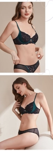 Detail of lace embroidery on deep green bra with pearl pendant and sheer mesh trim