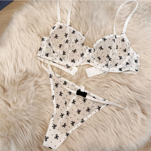 Détail de l'ensemble de lingerie en maille blanc cassé avec broderie nœuds noirs