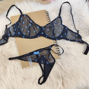 Détail à plat de lingerie en dentelle noire avec imprimé papillon bleu sur tapis moelleux