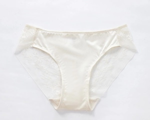 Detailed close-up of ivory satin panties with delicate floral lace and side embroidery