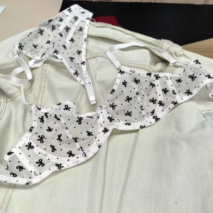 Détail d'un ensemble de lingerie en mesh blanc avec motifs nœuds noirs et pois
