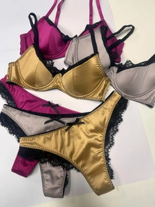 Detail von Satin- und Spitzenunterwäsche-Sets in Gold, Lila und Grau mit Schleifen