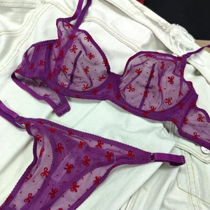 Détail d'un ensemble de lingerie en mesh violet avec des motifs de nœuds rouges