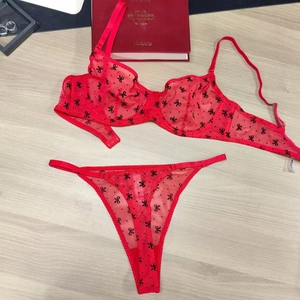 Ensemble de lingerie en tulle rouge avec motifs nœuds noirs sur fond de bois clair