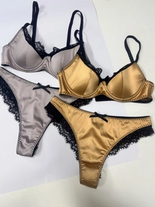Flach liegende Dessous-Sets aus Satin und Spitze in Gold und Silber mit Bogendetails