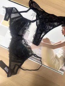 Detail of black floral lace lingerie showing intricate mesh texture and hook-and-eye closure
