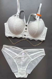 Detailed close-up of white lace lingerie set with gold chain and sheer mesh fabric