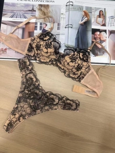 Flat lay of lace lingerie set with floral embroidery on light wood background