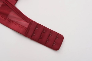 Close-up of wine red lace bra with three-row hook and eye closure and breathable mesh wing
