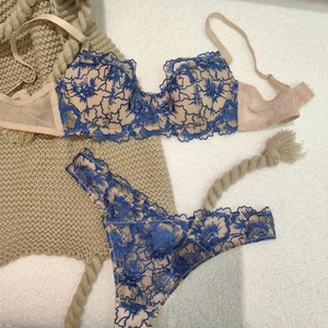 Detailed close-up of dark blue floral lace embroidery on a beige mesh lingerie set