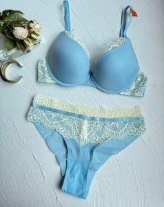 Flat lay of light blue lace lingerie set with floral embroidery and gold accessories
