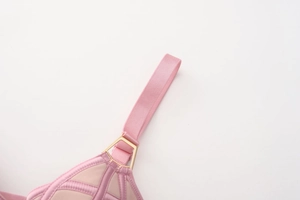 Detailed shot of pink satin shoulder strap with a gold metal ring on mesh bra