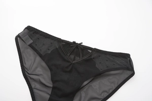 Detail of black mesh panties with polka dots, delicate bow and V-shape cross straps