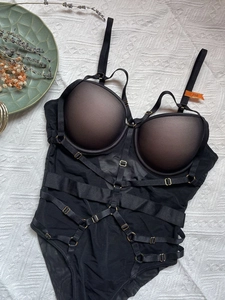 Detail of black strappy bodysuit with mesh fabric and underwire cups on white backdrop