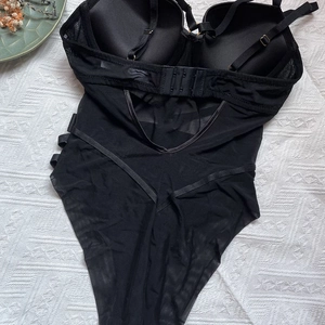 Detailed back view of a black mesh bodysuit featuring adjustable straps and hollow cutouts