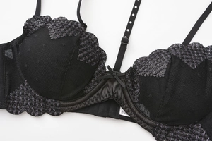 Close-up of black mesh bra featuring delicate silver embroidery and a satin bow