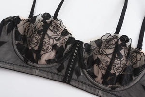Macro shot of black rose floral embroidery and sheer mesh lace on a supportive bra